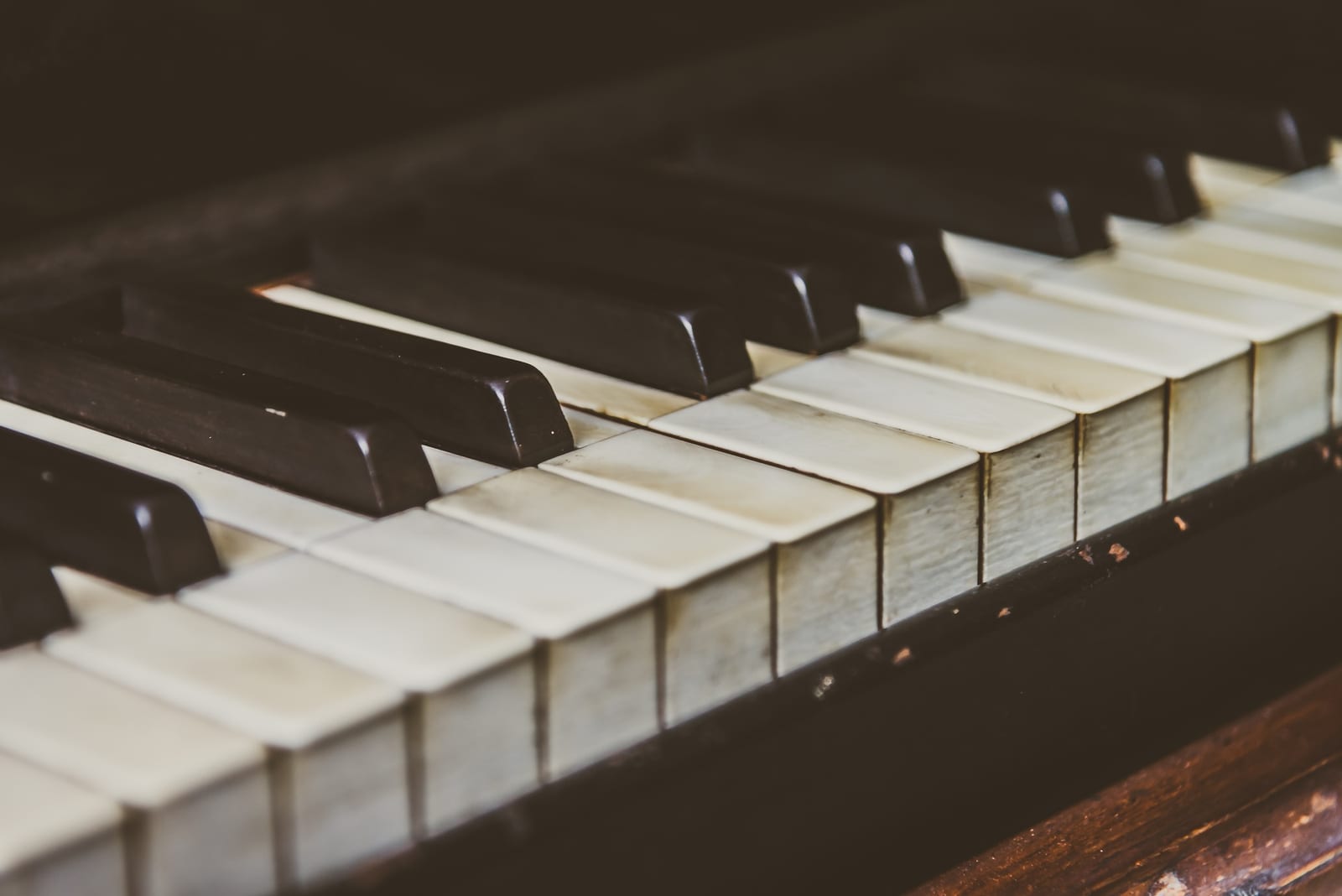 Piano vertical antigo com partitura sobre o banco, em estúdio claro